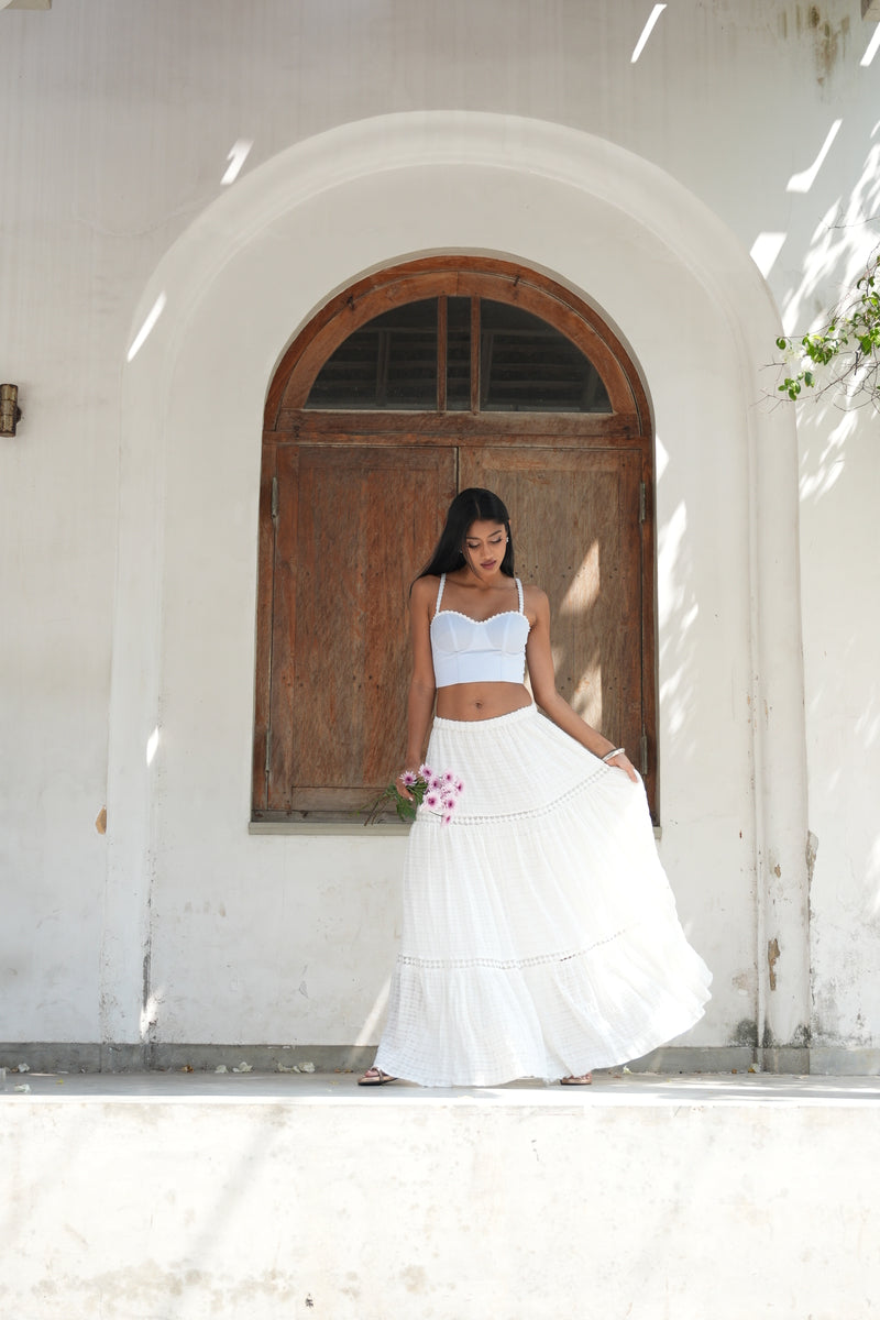 Woman in a white dress standing in front of a wooden door with arched top
